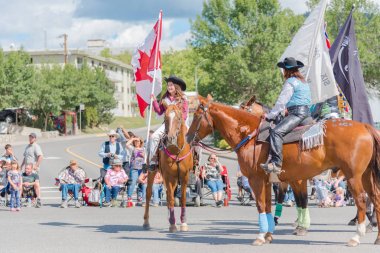 Williams Lake, British Columbia/Kanada - 2 Temmuz 2016: genç bir kız bir ata biniyor ve gururla popüler yıllık izdiham geçit töreni sırasında Kanada bayrağı taşır.