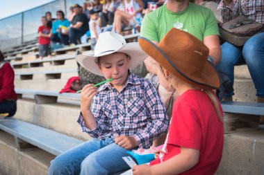 Williams Lake, British Columbia/Canada - July 1, 2016: two children enjoy a snow cone while watching the 90th Williams Lake Stampede, one of the largest stampedes in North America clipart