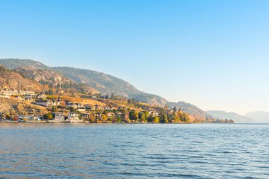 Waterfront evleri ve mavi gökyüzü ve sıcak sonbahar akşam güneş ışığı ile gölde dağlar