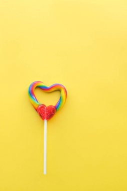 Sevimli kalp şeklinde gökkuşağı girdap lolipop düz sarı arka planlı portre biçimi hakkında