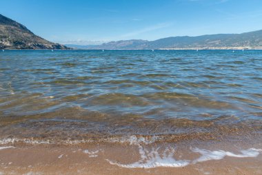 Yazın Penticton 'da Okanagan Gölü ve mavi gökyüzü manzaralı dalgalar Okanagan Sahili' ne vuruyor.