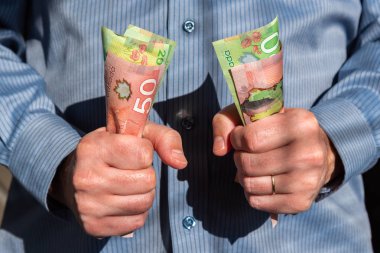 Kanadalı yirmi elli dolarlık banknotları sıkıca tutan adam.