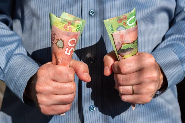 Kanadalı yirmi elli dolarlık banknotları sıkıca tutan adam.