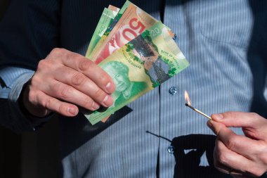 Kanada dolarlarının yanında yanan kibriti tutan adamın yakın çekimi