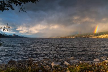 Okanagan Gölü 'nün üzerinden geçen dramatik fırtına bulutları ve yağmur Naramata üzerinde çift gökkuşağı manzaralı.