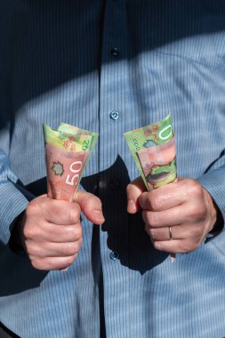Adam Kanada dolarlarını sıkıca göğsünün önünde tutuyor.