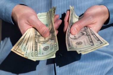 20, 10 ve 5 dolarlık banknotları uzatan adamın yakın çekimi.
