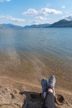 Okanagan Vadisi 'ndeki göl ve dağ manzaralı yürüyüş ayakkabıları içinde kadın ayakları.