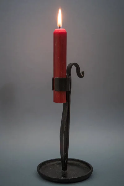 A candle holder with a red lighted candle