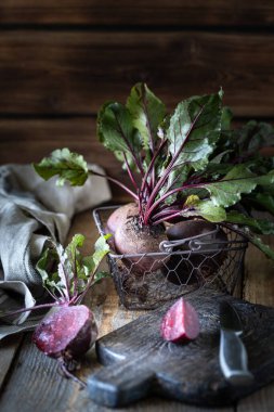 Tahta bir sepetin üzerinde yaprakları olan taze organik kırmızı pancarlar. Doğal organik sebzeler. Sonbahar hasadı. Kırsal