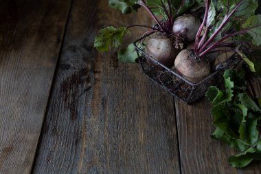 Tahta bir sepetin üzerinde yaprakları olan taze organik kırmızı pancarlar. Doğal organik sebzeler. Sonbahar hasadı. Taşralı. Boşluğu kopyala