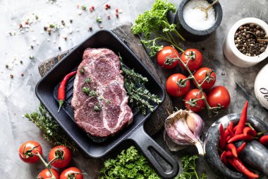 Çiğ taze et. Baharat, sebze ve otlar ile, bir ızgara tavada malzemelerle iki biftek. üst görünüm