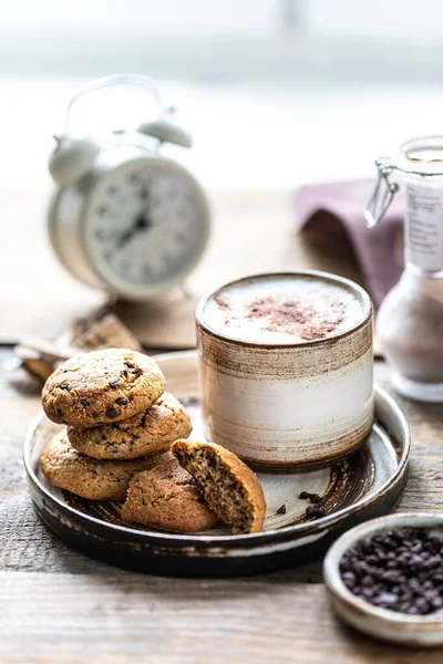 Domácí sušenky s ořechy a kávou v keramickém kelímku na dřevěném stole. Čas na kafe. Poplašné hodiny v pozadí. Snídaně — Stock fotografie