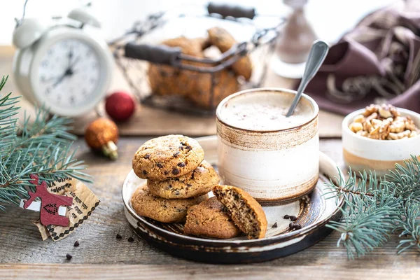 Домашнее печенье с орехами и кофе в керамической чашке на деревянном столе с игрушками и ветками елки — стоковое фото