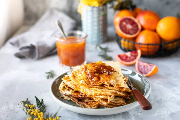Pancakes with jam or marmalade made from red orange. Tasty breakfast. Crepe suzette pancakes with orange sauce.