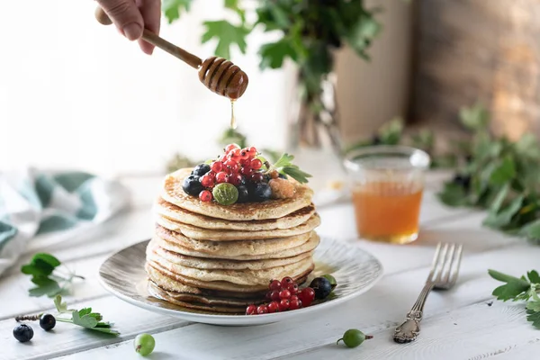 Pfannkuchen mit frischen Himbeeren, Johannisbeeren, Blaubeeren, Honig und Tee — Stockfoto