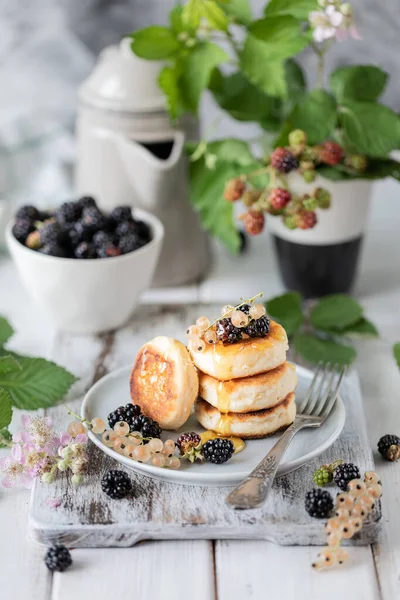 Panquecas caseiras com bagas, amoras, mel no prato, um ramo de um despertador BlackBerry no fundo de madeira branca — Fotografia de Stock