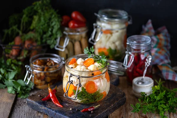 在深色木制桌子上的玻璃瓶里放有胡萝卜的开花椰菜。 发酵食品. — 图库照片