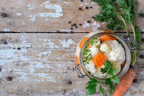 Ingelegde bloemkool met wortelen in een glazen pot op een oude houten tafel. Gefermenteerd voedsel. Begrepen, ruimte. bovenaanzicht — Stockfoto