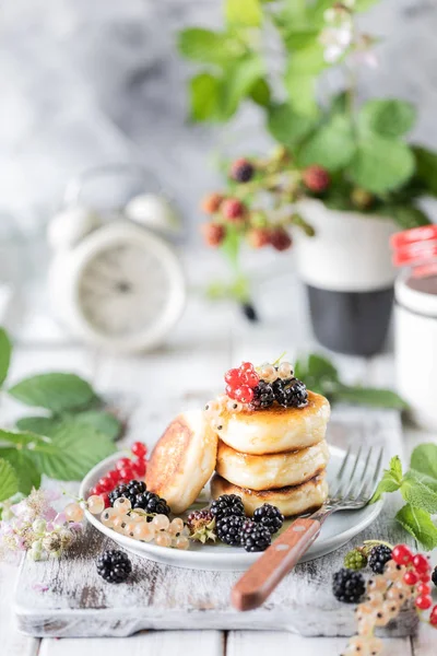 Panquecas caseiras com bagas, amoras, mel no prato, um ramo de um despertador BlackBerry no fundo de madeira branca — Fotografia de Stock
