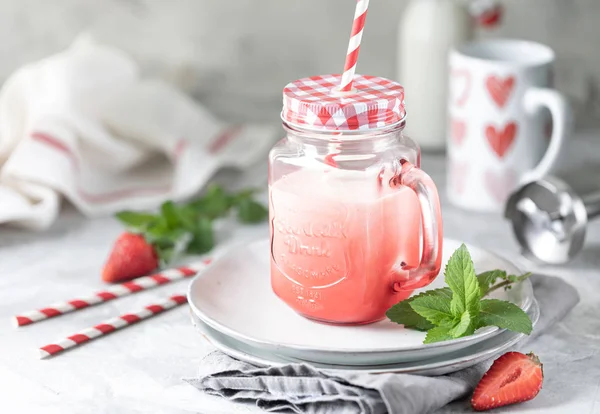 Strawberry and milk or yogurt smoothies in a beautiful red glass jar and sprigs of mint on a white concrete table. The recipe for the holiday Valentine's Day. Copy space — Stock Photo, Image