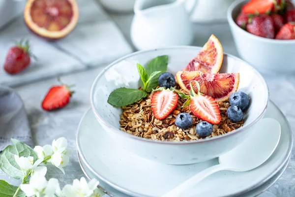 Здоровый завтрак с мюсли, йогуртом, фруктами, ягодами на белой тарелке . — стоковое фото