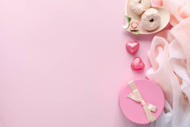 Dizüstü bilgisayarı ve kadın aksesuarlarıyla moda blogcusu çalışma alanı soluk pembe masada kozmetik ürünleri. Sevgililer Günü için tatlı, çörek, kurabiye ve hediyeler. düz yatış, üst görünüm
