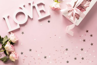 Hediye kutusu ya da hediye kutusu ve pembe masa manzaralı çiçekler. Düz yatıyordu. Doğum günü, düğün, sevgililer günü, 8 Mart konsepti. Boşluğu kopyala