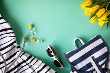 Güzel çizgili yaz elbisesi, sırt çantası ve bir buket çiçek. Yaz modası, düz yatak, tatil konsepti. Kopyalama alanı olan üst görünüm