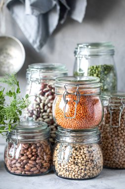 Ahşap bir masada cam kavanozlarda farklı baklagiller. Vejetaryenler için bir protein kaynağı. Sağlıklı beslenme konsepti. Dikey