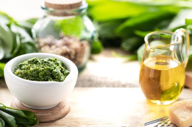 Tahta bir masanın üzerinde seramik havan topu içinde zeytinyağı ve parmesan peynirli yaban pırasası pesto. Ramson 'ın kullanışlı özellikleri. Çerçeve