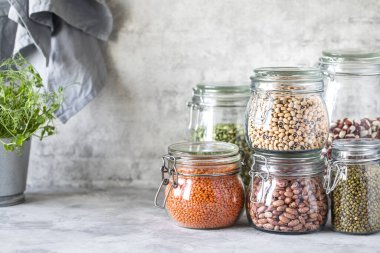Ahşap bir masada cam kavanozlarda farklı baklagiller. Vejetaryenler için bir protein kaynağı. Sağlıklı beslenme konsepti. Boşluğu kopyala