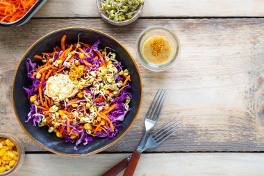 Havuçlu, soğanlı, mısırlı, ahşap bir tabakta gübre tohumu bulunan taze kırmızı lahana salatası. Seçici odaklanma. Üst Manzara. Uzayı kopyala yatay