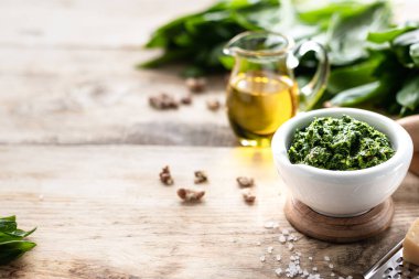 Tahta bir masanın üzerinde seramik havan topu içinde zeytinyağı ve parmesan peynirli yaban pırasası pesto. Ramson 'ın kullanışlı özellikleri. Çerçeve