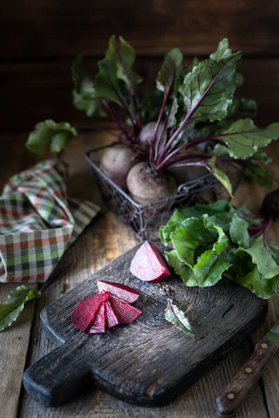 Fresh organic red beets with leaves in a wicker basket on a wooden table. Natural organic vegetables. Autumn harvest. Rustic country style.