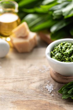 Tahta bir masanın üzerinde seramik havan topu içinde zeytinyağı ve parmesan peynirli yaban pırasası pesto. Ramson 'ın kullanışlı özellikleri. Boşluğu kopyala.