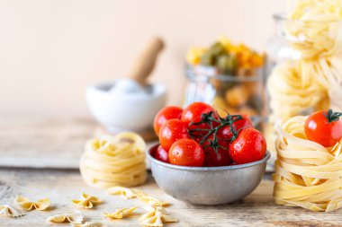 Sarı ahşap bir masada cam kavanozlarda farklı İtalyan makarnaları..