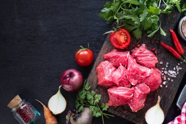 Çiğ biftek filetosu ızgara için hazır. Tahta kesme tahtasındaki dana filetosu, kiraz domatesleri, acı biber ve bitkilerle birlikte. Çorba ya da borç için malzemeler. kopyalama alanı. en üstteki görünüm