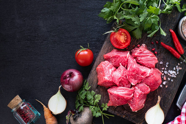 Raw beef fillet ready for grilling. Veal fillet on a wooden cutting board with cherry tomatoes, hot pepper and herbs. Ingredients for soup or borsch. copy space. top view