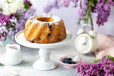 Hafif arka planda böğürtlen, buket ve leylaklı ev yapımı kek.