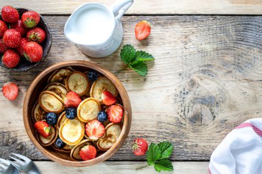 Tahta bir kasede küçük krep mısır gevreği ve çikolatalı mini krep ve ahşap bir arka planda bal ve çilek. Üst Manzara. Boşluğu kopyala