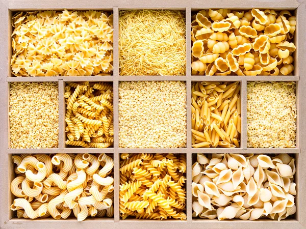 Different types of italian uncooked pasta in wooden box, whole wheat pasta, pasta, spaghetti, noodles, tagliatelle. Top view