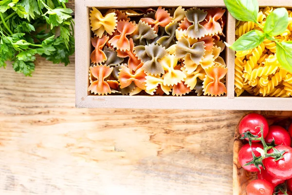 Different types of italian uncooked pasta in wooden box, whole wheat pasta, pasta, spaghetti, noodles, tagliatelle. Top view. — Stock Photo, Image