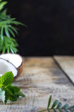 Tahta bir masanın üzerinde yarım hindistan cevizi ve bir palmiye dalı var. Boşluğu kopyala.