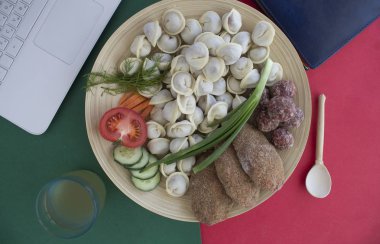 Laptop, meyve suyu, hamur tatlısı, sebzeler masanın üstünde.