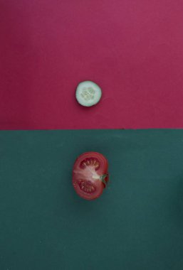 Kırmızı ve yeşil arkaplanda taze domates ve salatalık, metin için yer var.