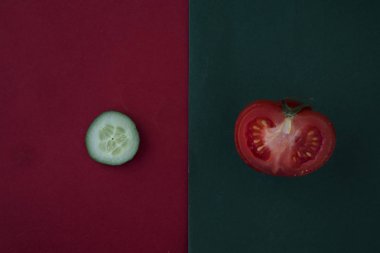 Kırmızı ve yeşil arkaplanda taze domates ve salatalık, metin için yer var.