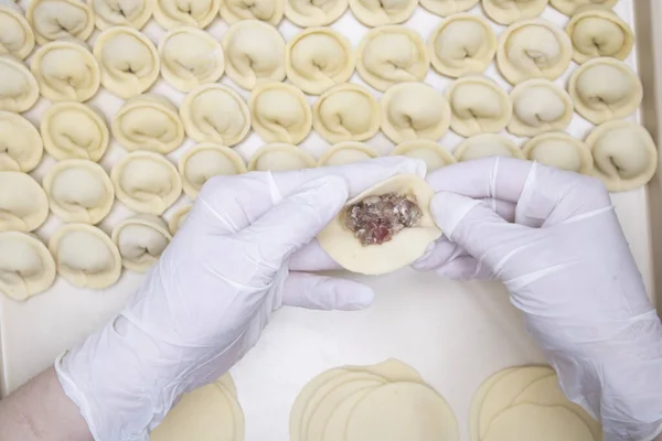 Annenin elleri pelmeni 'yi kıyma ile tutuyor.