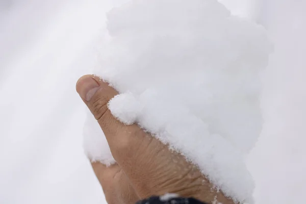 Een man met sneeuw in de palm, zonder handschoenen — Stockfoto