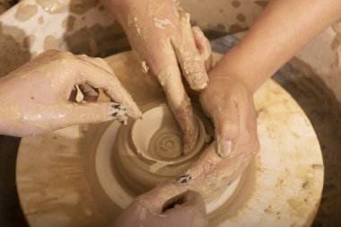 Bir çömlekçinin elleri, çemberin üstünde toprak kavanozu yaratıyor.